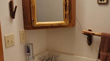 A bathroom with a wooden vanity, a large mirror with lights, and a towel rack.