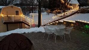 A patio with a round table and chairs, a covered seating area, and a staircase with railings. - Trickling Waters Retreat (Marquette)