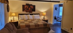 A bedroom with a large bed, two bedside tables with lamps, a star decoration on the wall, and a chair in the corner. - Trickling Waters Retreat (Marquette)