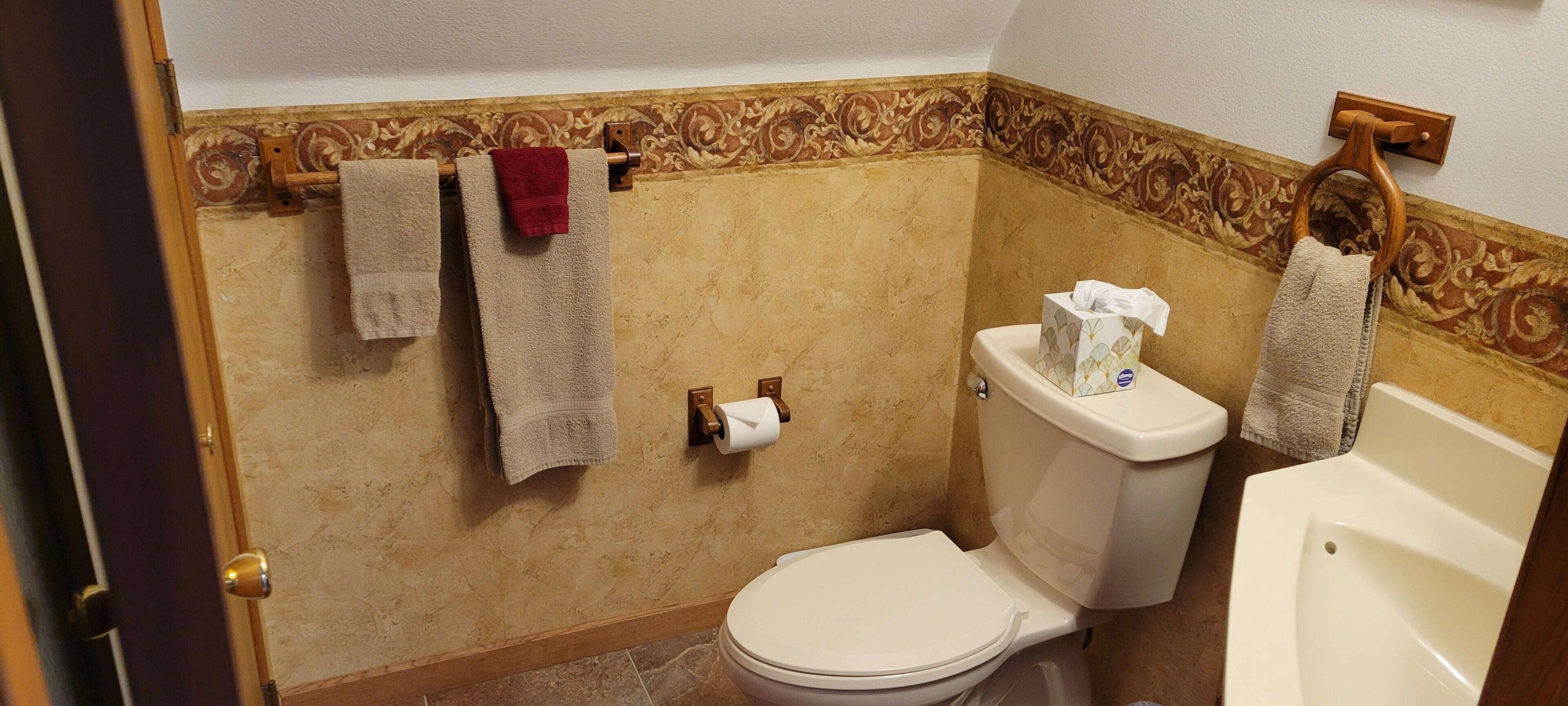 Un baño con inodoro, bidé y toallas colgadas en un perchero.