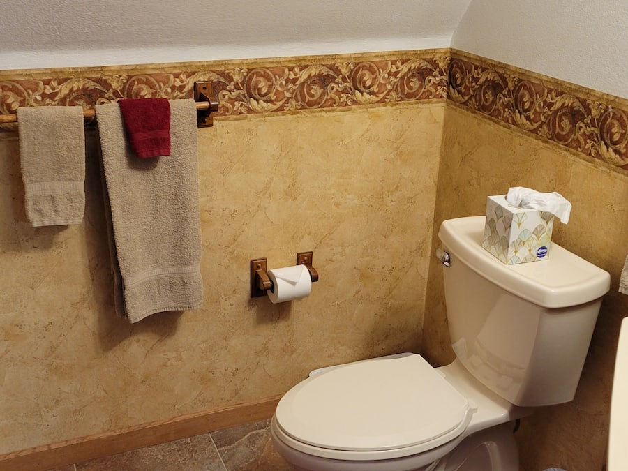 Un baño con inodoro, bidé y toallas colgadas en un perchero.