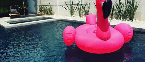 Una piscina al aire libre, sombrillas, sillones reclinables de piscina