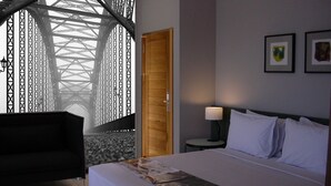 Une chambre d’hôtel avec un lit, une table de chevet, une lampe, une chaise et une fenêtre donnant sur un pont.