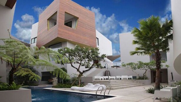 Un bâtiment moderne doté d’une architecture géométrique originale, d’une piscine et d’un aménagement paysager de style tropical.