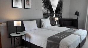 Una habitación de hotel moderna con una cama grande, dos mesitas de noche y una mesilla.