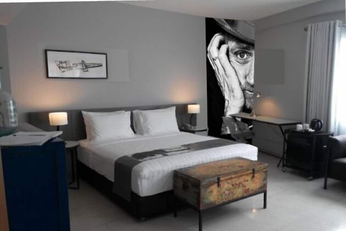 A modern hotel room with a large bed, bedside tables, a desk, and a chair.