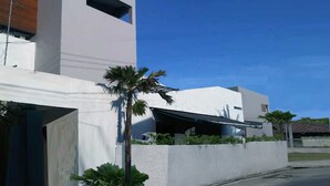 Un bâtiment moderne avec une façade blanche, une partie en bois inclinée et une petite fenêtre.