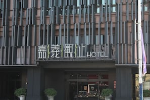 Un hotel con fachada moderna, caracterizada por líneas verticales y un cartel llamativo con el nombre del hotel.