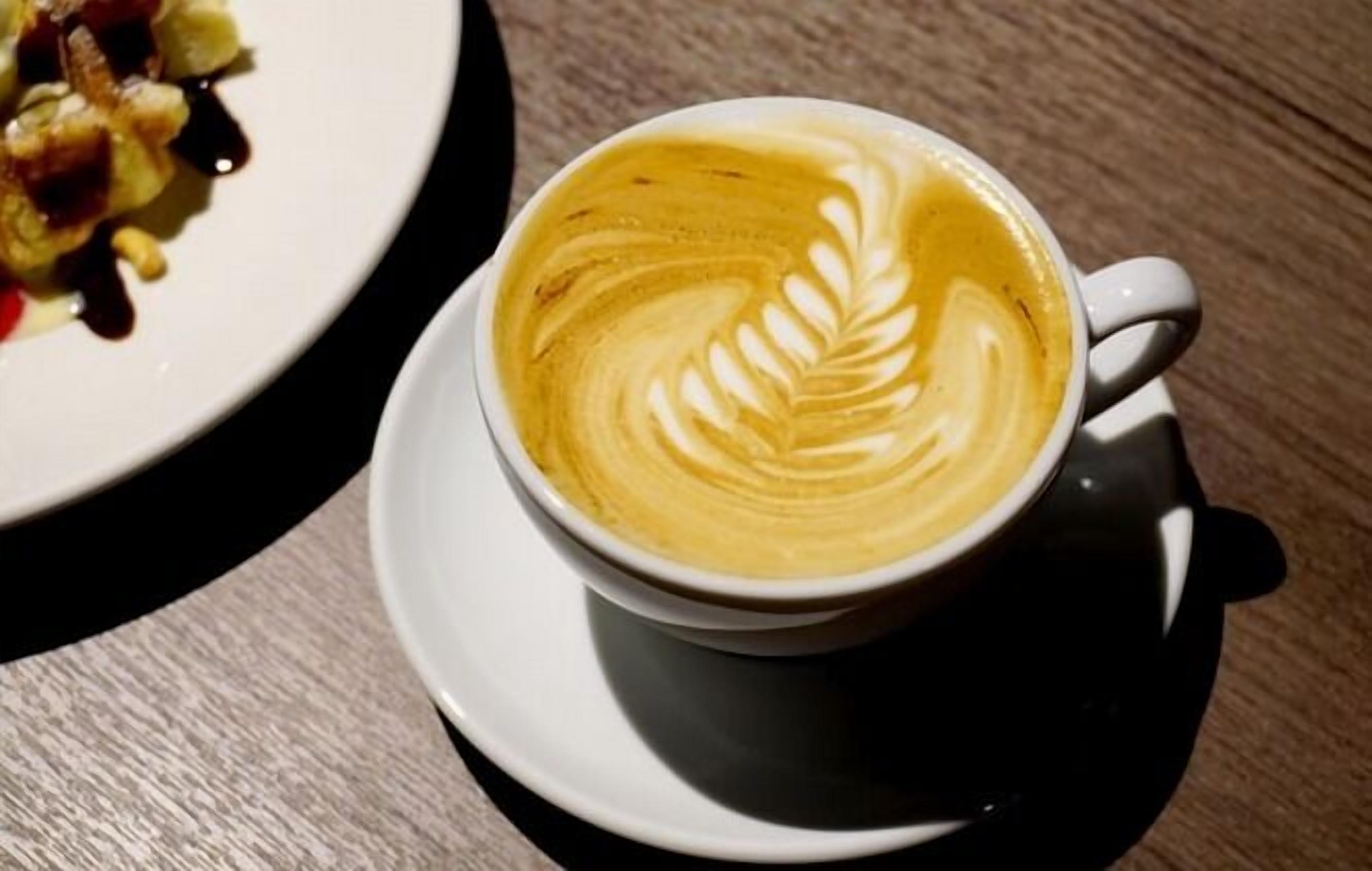 A cup of coffee with latte art on a saucer.