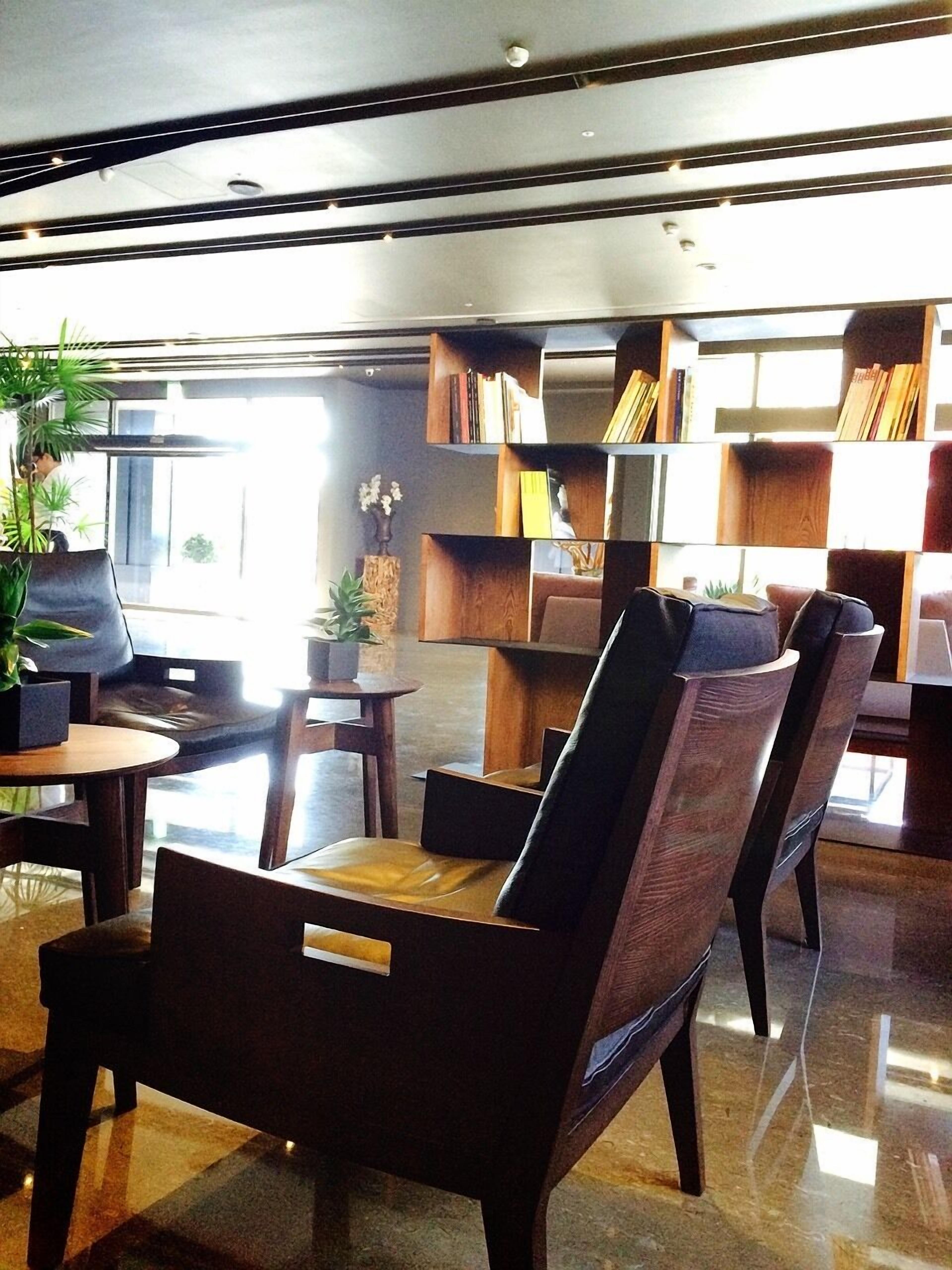 Un'area lounge moderna con poltrone in pelle, un tavolino da caffè e una libreria piena di libri.