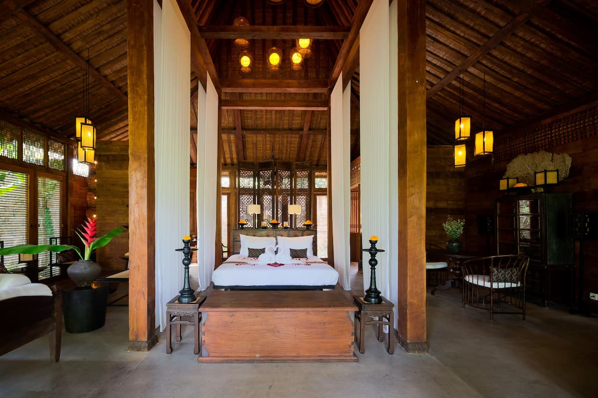 A traditional room with a wooden ceiling, a bed with white linens, and a wooden bench.