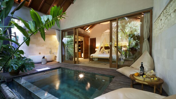 Ein luxuriöses Schlafzimmer mit einem großen Bett, einem verglasten Badezimmer und einem Poolbereich.
