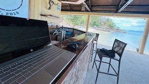 A bar area with a laptop, a metal container, and a chair.