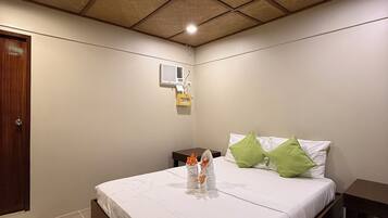 Habitación de hotel con una cama, una mesita de noche, una puerta de madera y un techo con diseño de cuadrícula.