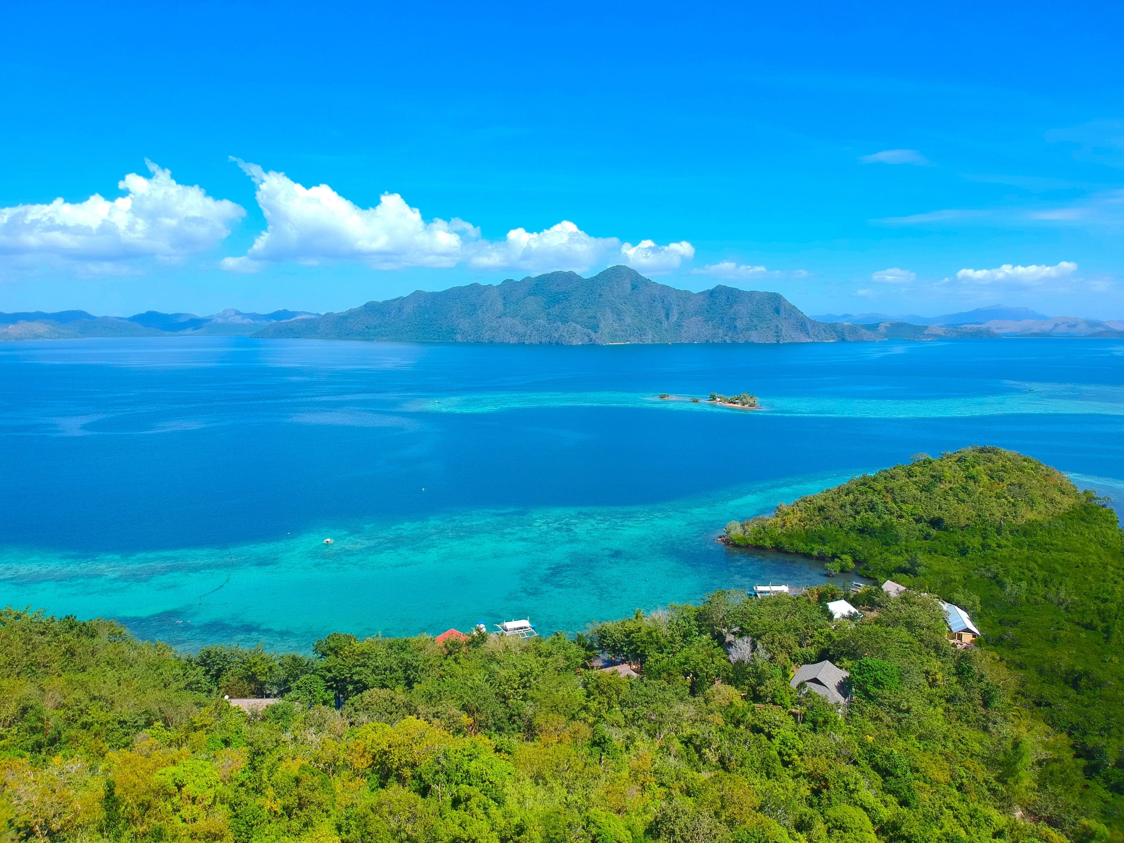 A coastal landscape with a small island, clear blue waters, and lush greenery.