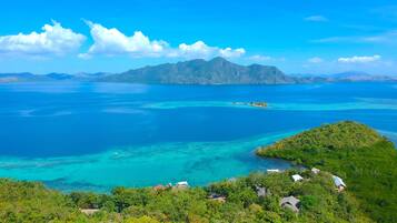 A coastal landscape with a small island, clear blue waters, and lush greenery.
