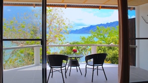 A balcony with two chairs and a table, overlooking a scenic view of a lake and mountains.