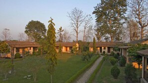 A courtyard with multiple buildings, a central pathway, and surrounding greenery. - Nepal Wildlife Resort (Thakudwara)