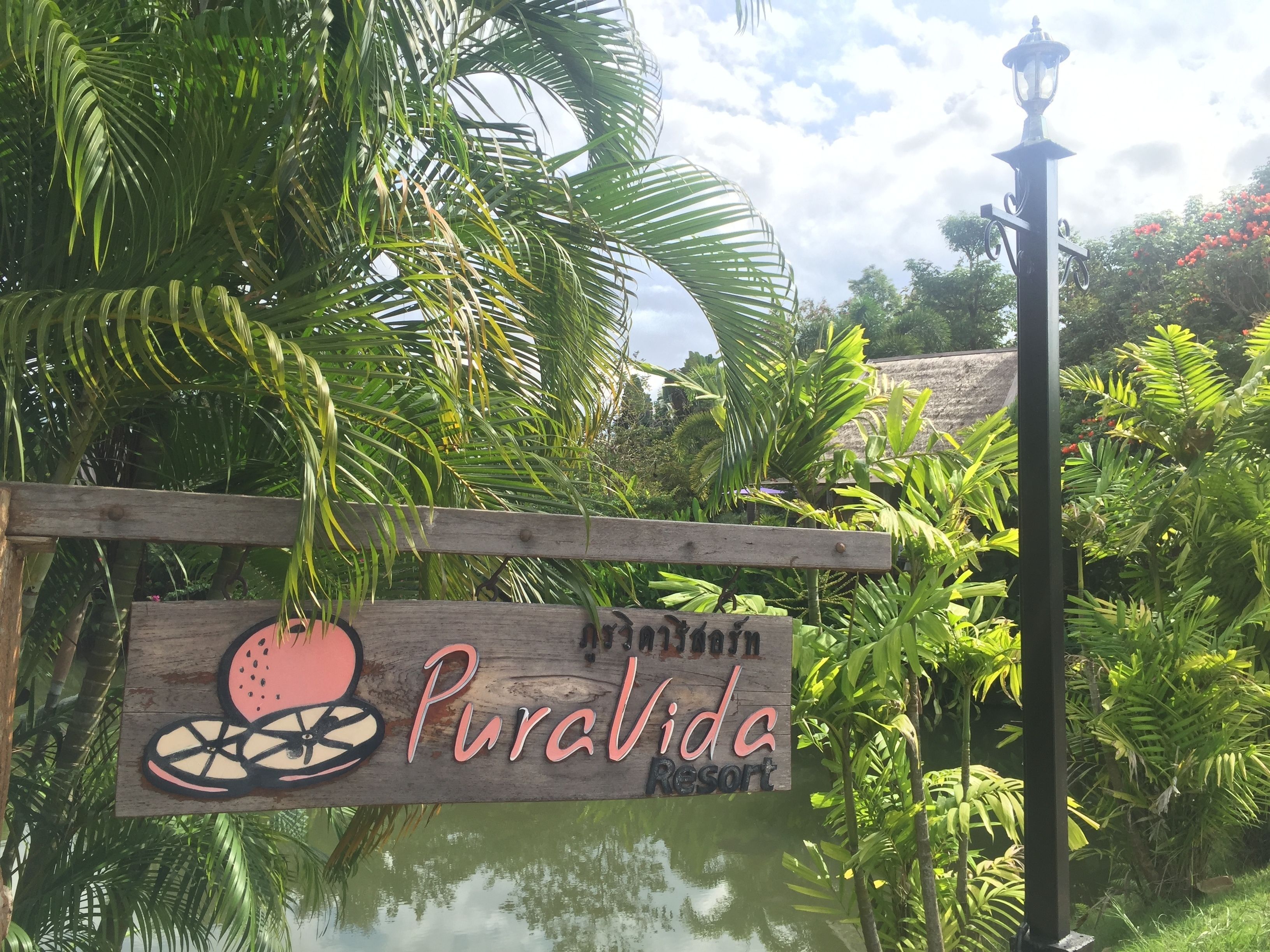 A wooden sign with a watermelon graphic and the text "PuraVida Resort".