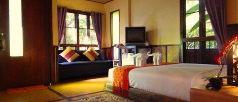 A room with a bed, a sofa, a television, and a window with curtains.