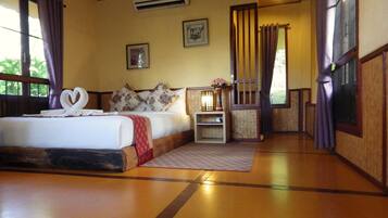 A hotel room with a bed, a bedside table with a lamp, and a window with curtains.