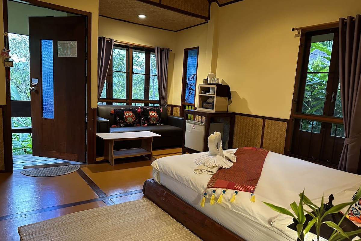Una habitación con una cama, un sofá, una mesita y una ventana con cortinas.