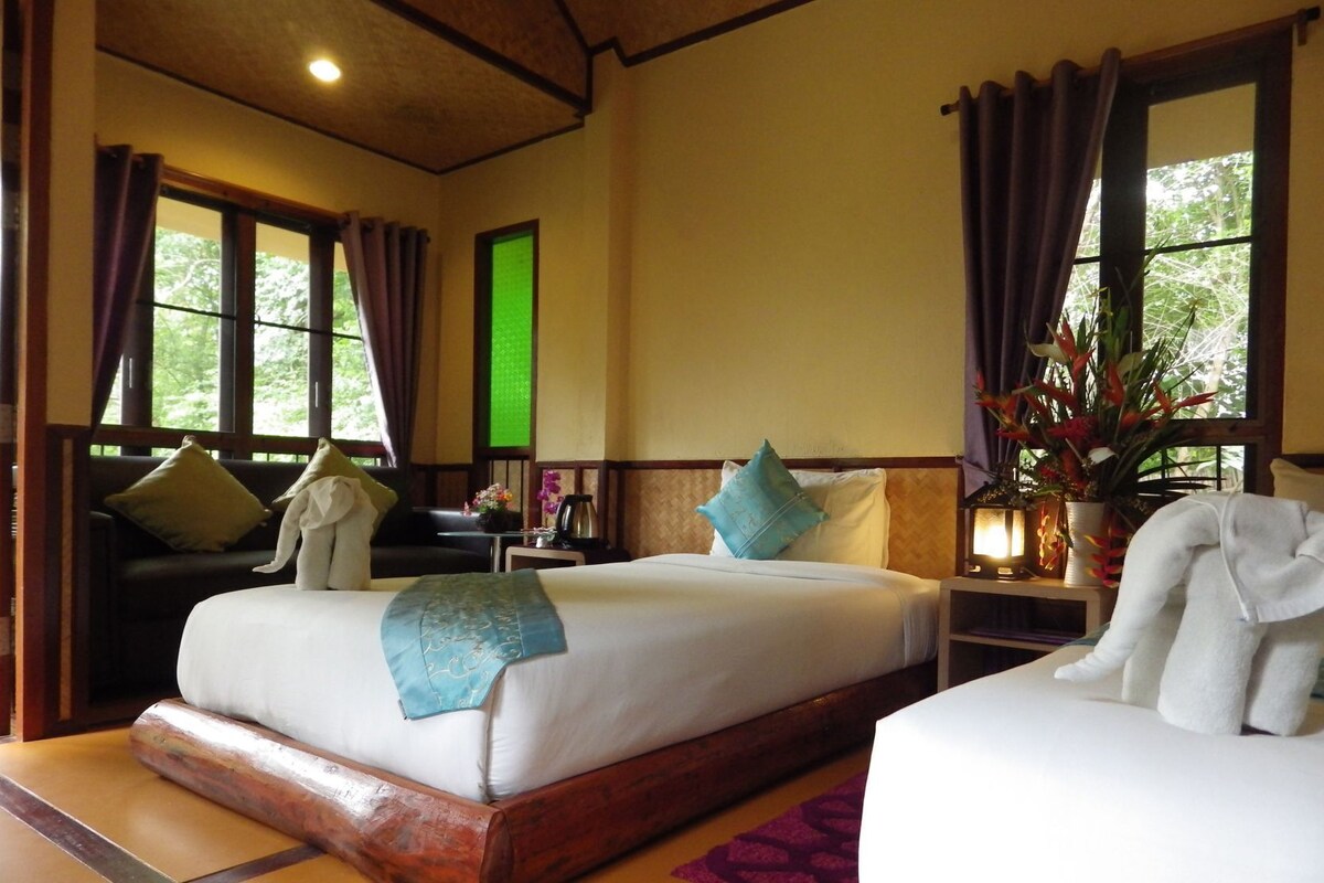 A room with two beds, a desk, and a window with curtains.