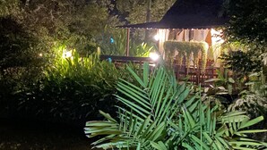 A nighttime garden with a gazebo, surrounded by dense foliage and illuminated by ambient lighting. - PuraVida Pai Resort (Pai)