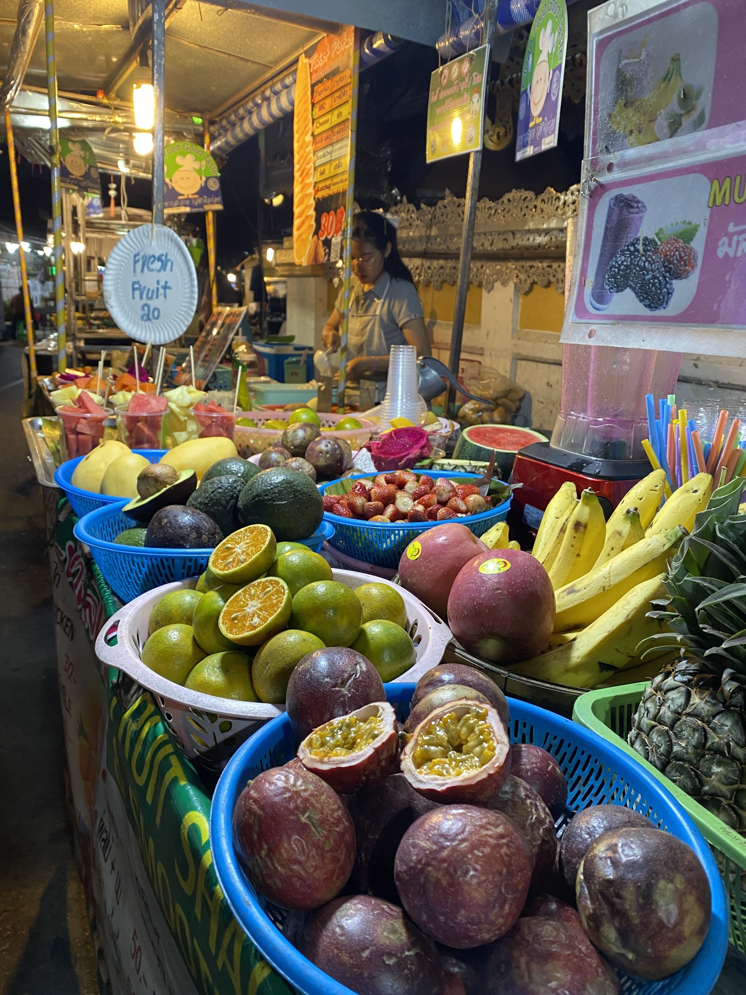 A fruit stand with various fruits and a sign indicating fresh fruit.
