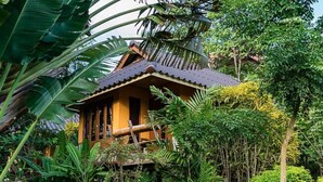 A traditional wooden house surrounded by lush tropical vegetation. - PuraVida Pai Resort (Pai)