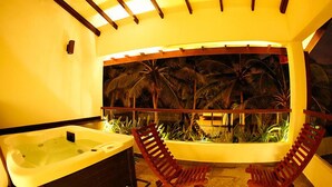 A room with a hot tub, two red chairs, and a large aquarium with tropical plants. - Blue Beach (Wadduwa)