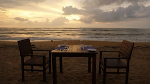 A beach table set with chairs facing the ocean at sunset. - Blue Beach (Wadduwa)