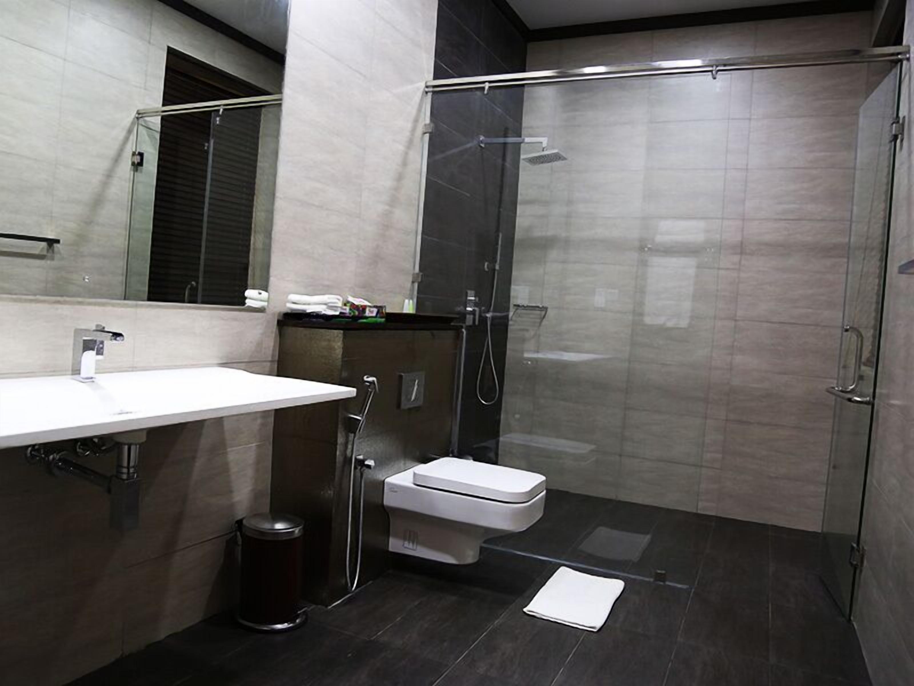 Un baño moderno con un lavamanos blanco, un inodoro y una zona de ducha con mampara de vidrio.
