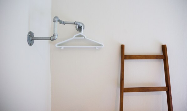 A wall-mounted metal pipe, a white plastic hanger, and a wooden ladder. - Krabi Pitta House (Krabi)