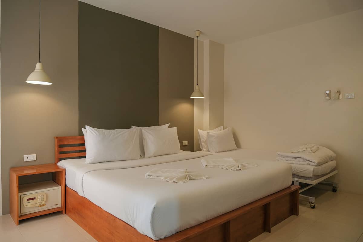 A neatly made double bed with white linens, a wooden headboard, and a bedside table with a radio.