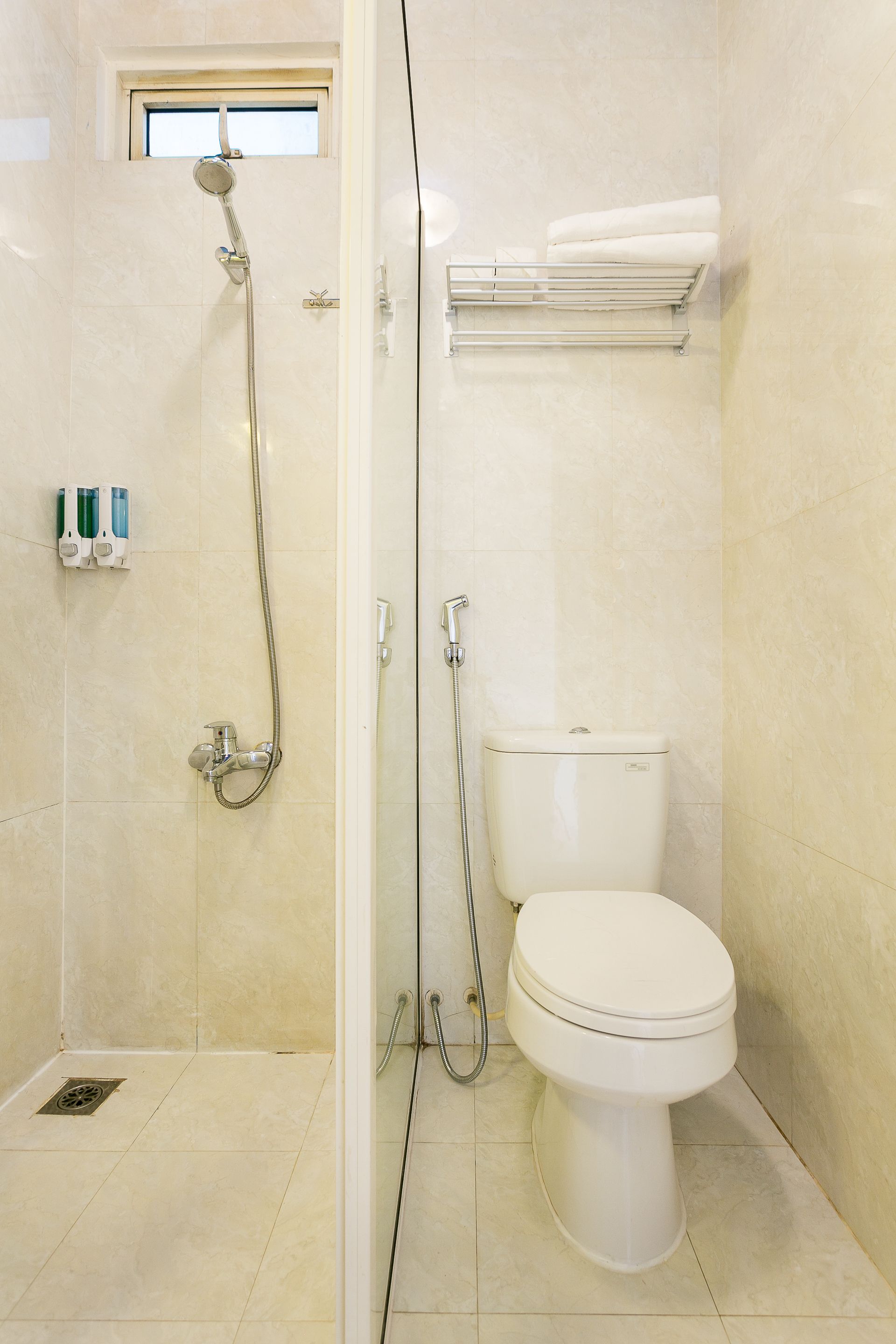Ein Badezimmer mit Dusche, Toilette und einem kleinen Fenster.