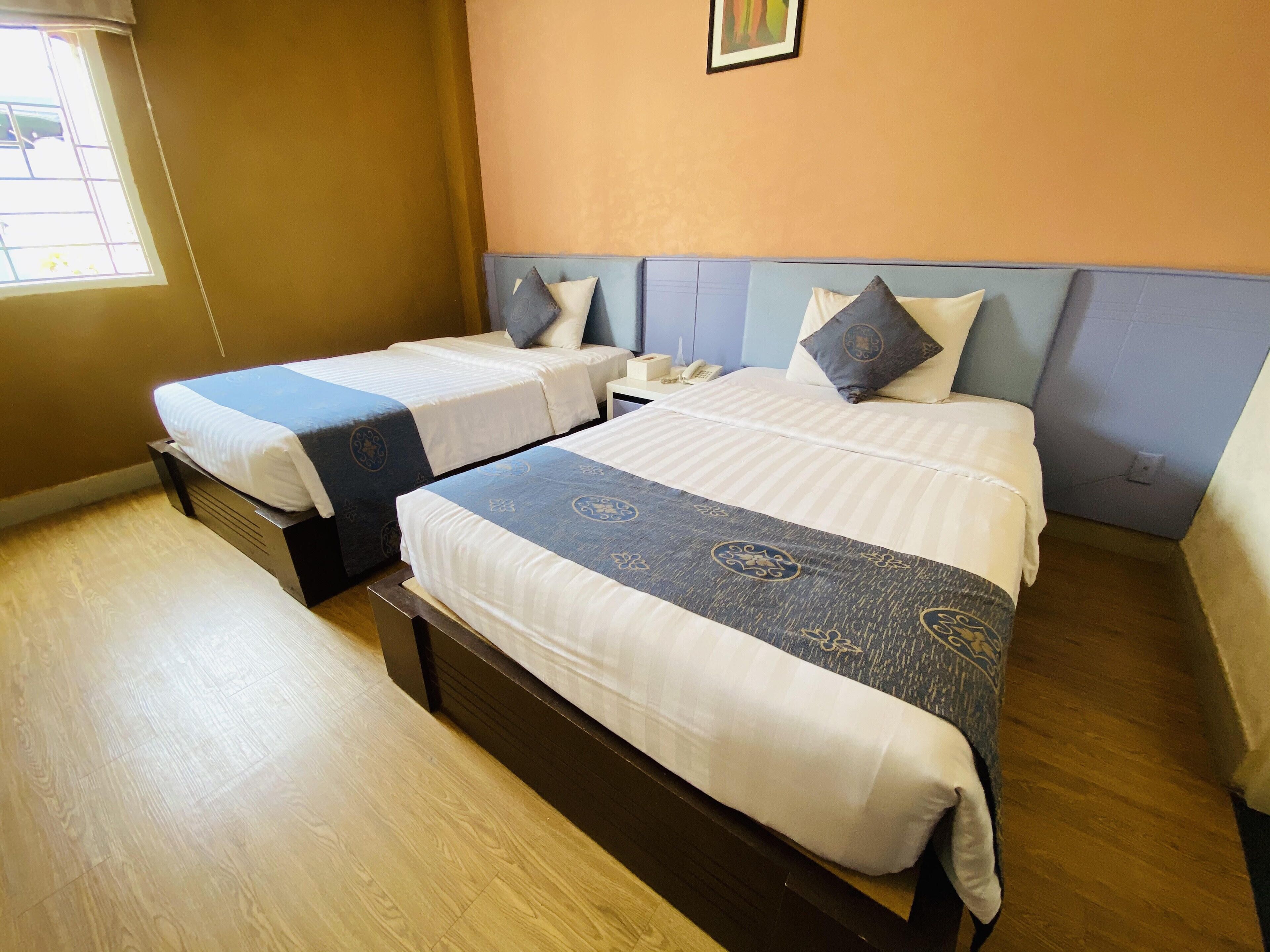 Una habitación de hotel con dos camas, un ventanal y un cuadro en la pared.