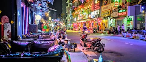 Cena de rua com mesas ao ar livre e uma moto estacionada na calçada.