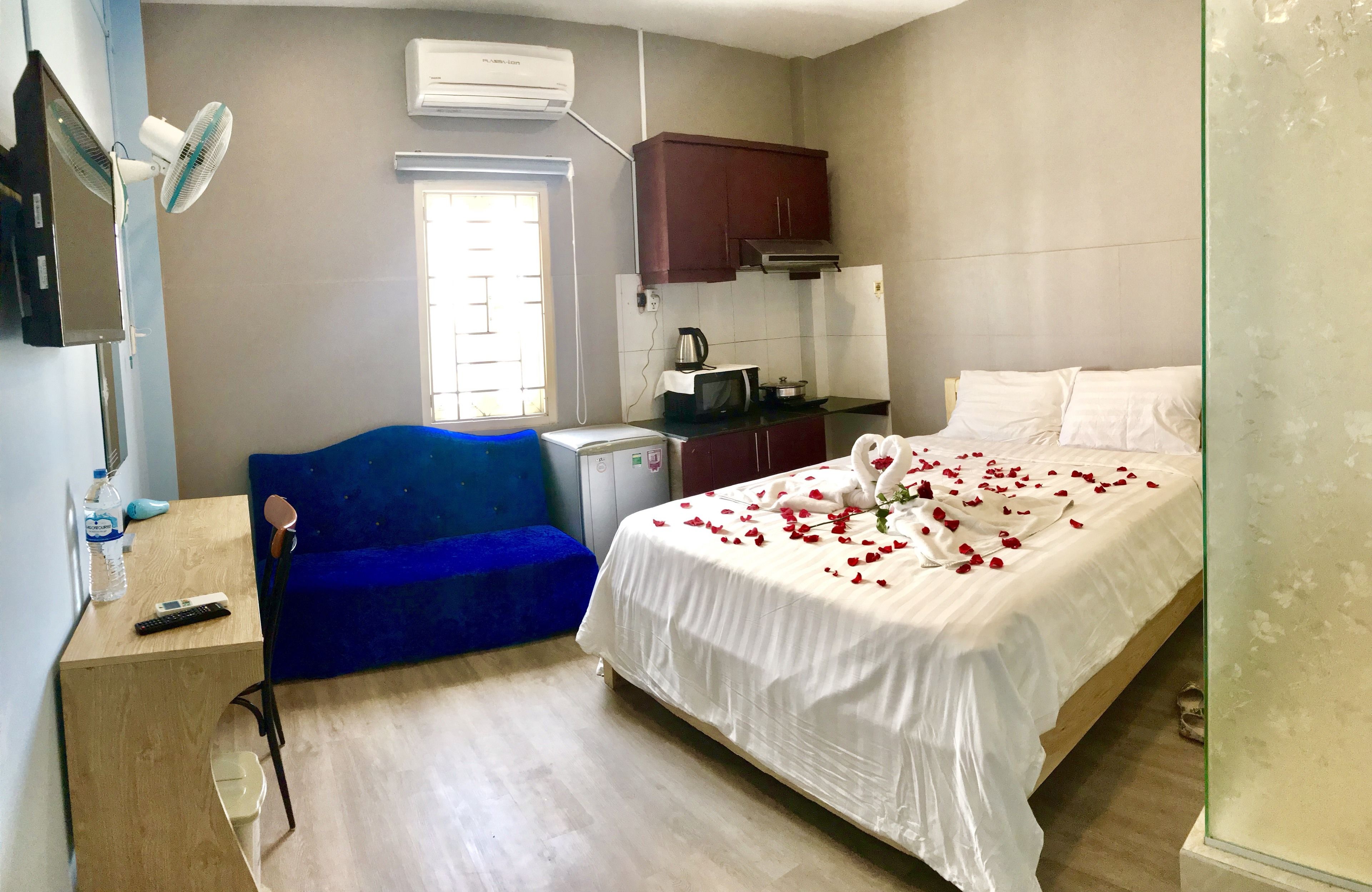 Ein Schlafzimmer mit einem Bett, einem blauen Sofa, einem Schreibtisch mit Stuhl, einer Mikrowelle und einer Klimaanlage.
