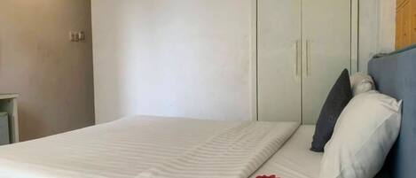 Un dormitorio con cama, armario y mesita de noche.