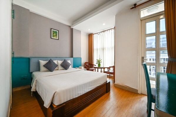 A hotel room with a bed, a small table with chairs, a window with curtains, and a view of the outside. - 99 Bui Vien Hotel (Ho Chi Minh City)