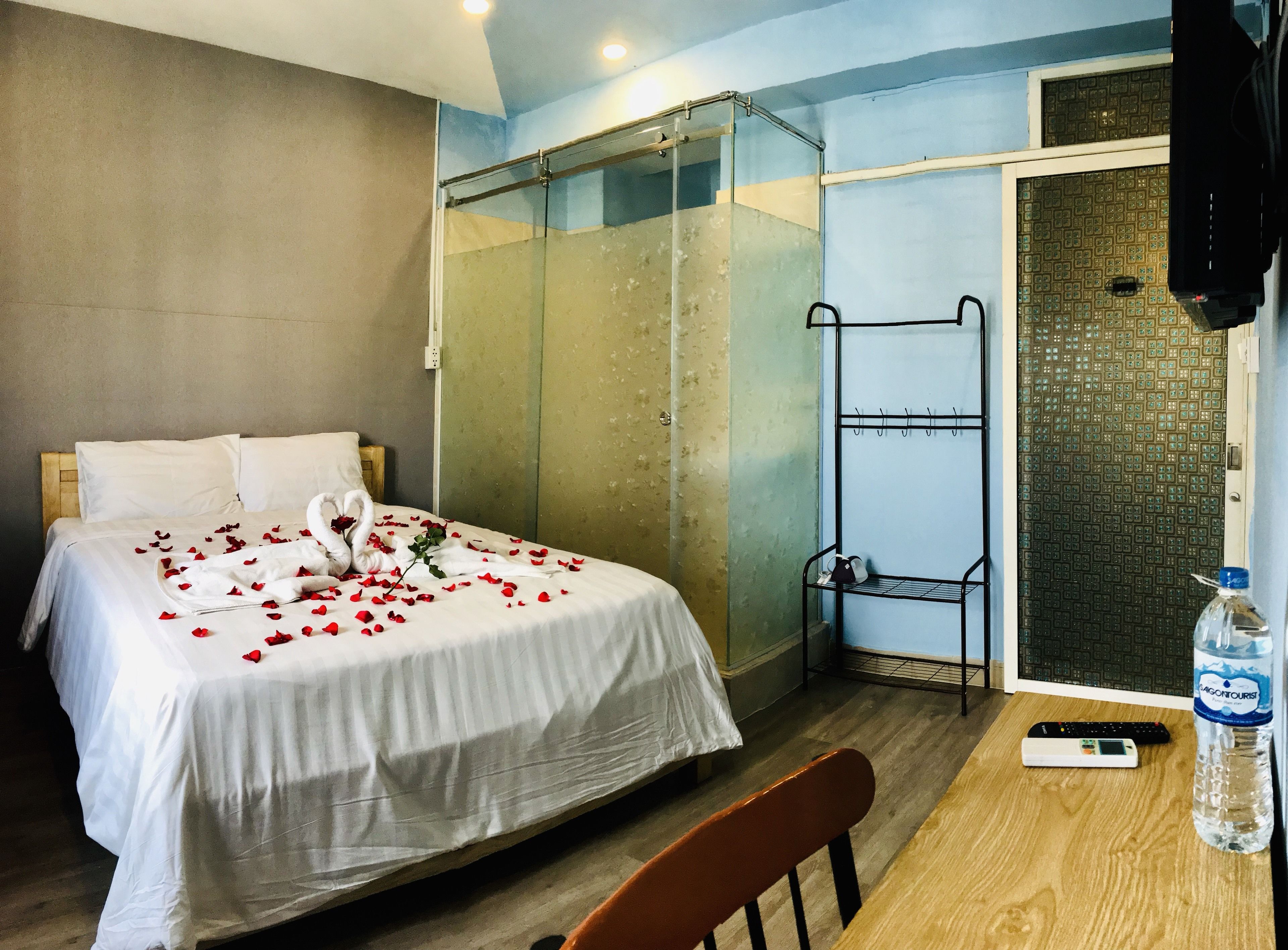 Une chambre d’hôtel avec un lit, une douche, une petite table avec une bouteille d’eau et une chaise.