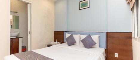 A hotel room with a bed, a nightstand, a bathroom, and a window with curtains.