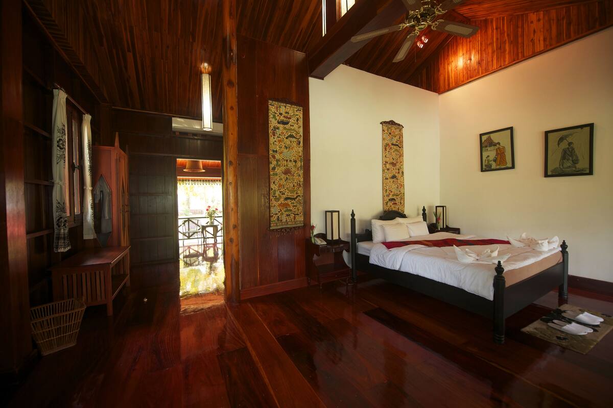A traditional wooden room with a bed, a wooden wardrobe, and a small table.