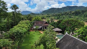 A traditional house with a thatched roof, surrounded by lush greenery and a pool. - Nam Ou Riverside Hotel & Resort (Pak Ou)