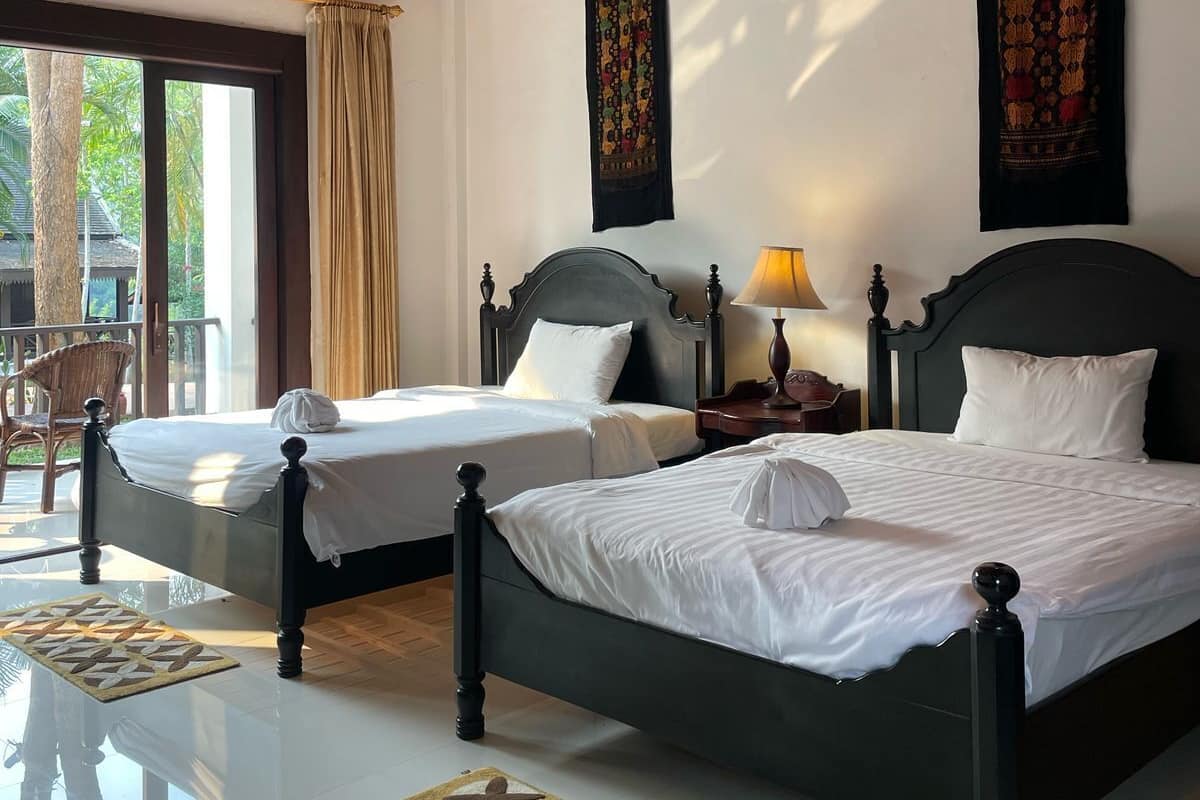 A hotel room with two beds, a ceiling fan, and a large window with curtains.