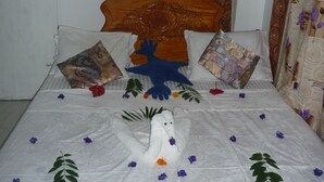 Un llit amb capçalera de fusta, almoinades amb estampat floral i una disposició decorativa de tovalloles.