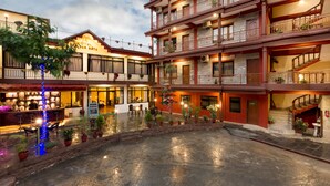 Un hotel de varios pisos con balcones, un patio y mesas al aire libre.