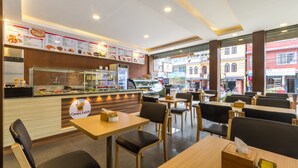 Un interior de restaurante con mostrador, carteles de menú y zona de mesas.