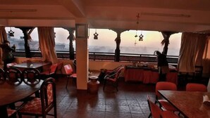 An indoor dining area with tables and chairs, a view through a window, and a railing. - Heart of Bhaktapur (Bhaktapur)